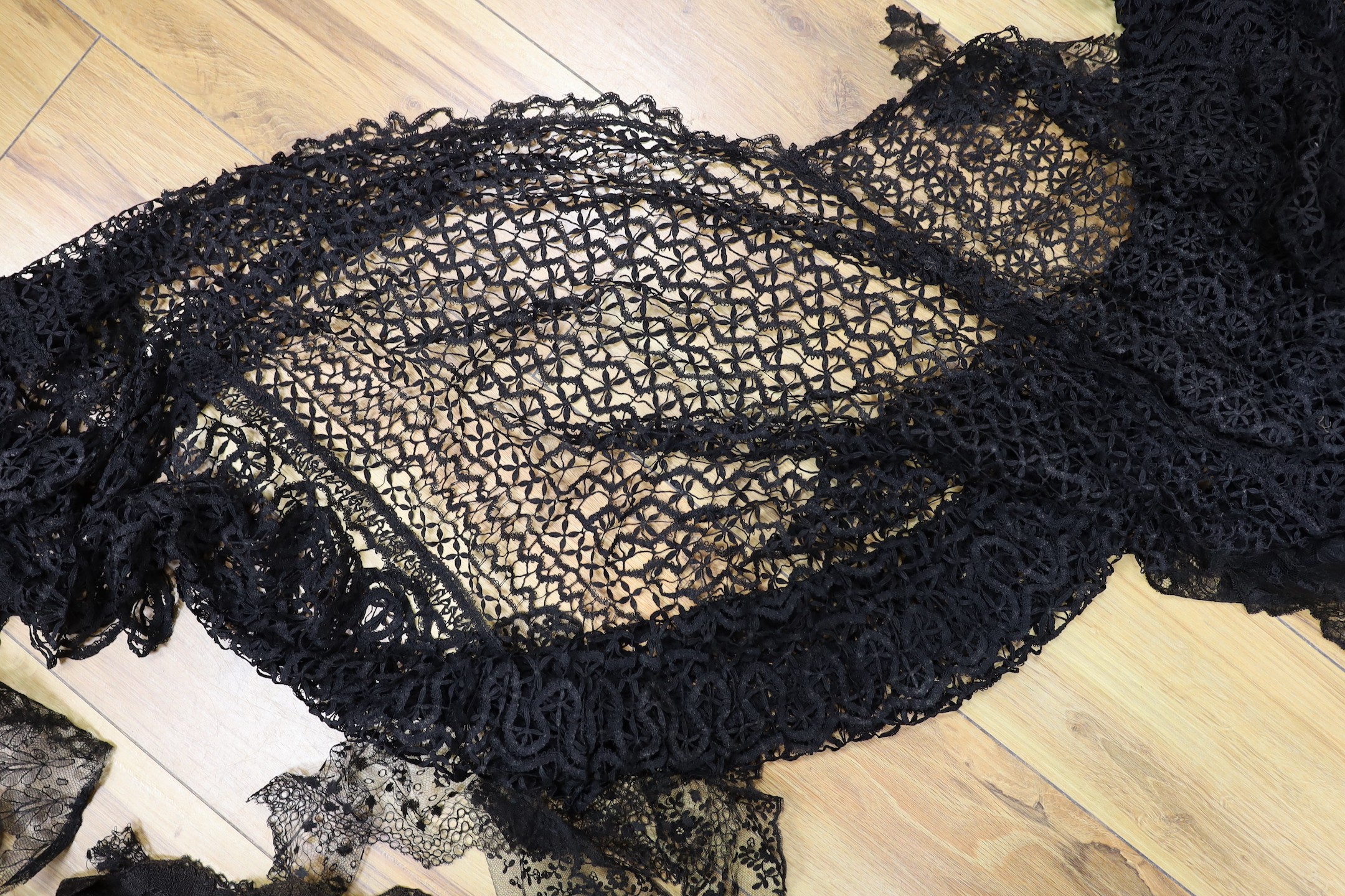 A quantity of mixed bobbin and black machine lace panels and trim